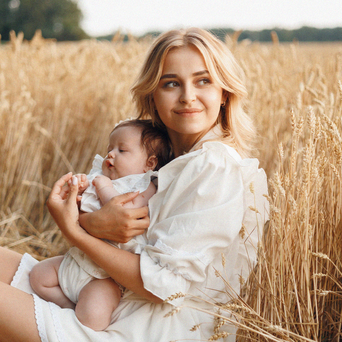 Maman et son bébé assis dans un champs de blé